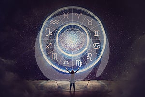 Woman raising hands looking at the night sky. Astrological wheel projection, choose a zodiac sign. Trust horoscope future