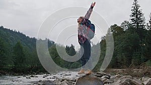 Woman raising hands in mountain landscape. Female traveler feeling freedom