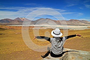 Woman Raising Her Arms In Front of Awesome View of Salar de Talar salt Lakes and Cerro Medano Mountain, Chilean Andes, Northern Ch photo