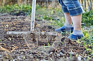 Woman raking soil with old rusty rake