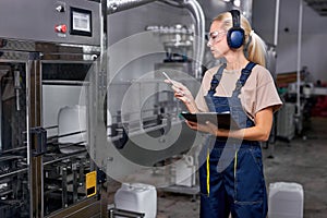 woman rate the quality of pesticides production in factory, take notes, in uniform