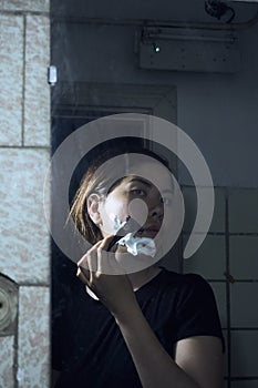 Woman with razor and shaving foam on her face