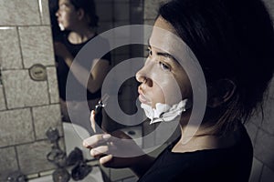 Woman with razor and shaving foam on her face