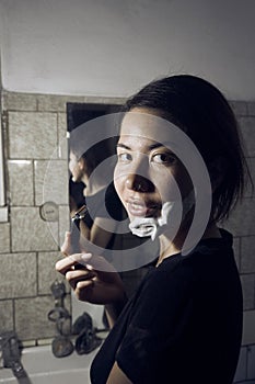 Woman with razor and shaving foam on her face