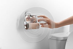 Woman reaching for empty toilet paper roll in bathroom, closeup