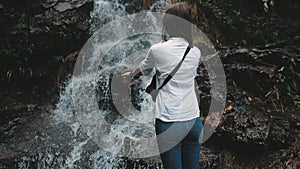 Woman reaching out hands to splashing waterfall