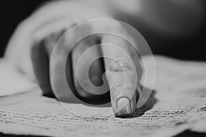 Woman reading ancient book - Bible. Concentrated attentively follows finger on paper page in library. Old archival