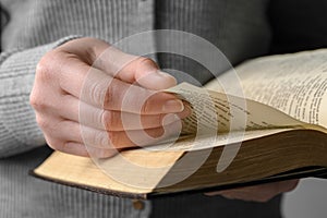 Woman reading Bible against grey background, closeup