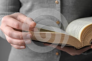 Woman reading Bible against grey background, closeup