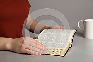 Woman reading Bible at light table, closeup