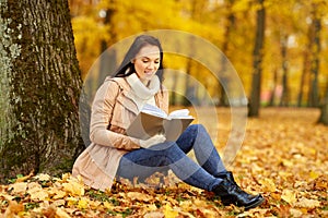 Woman reading book at autumn park
