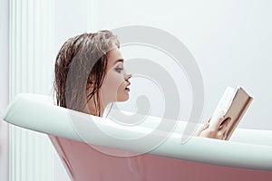 Woman reading book in bath tube