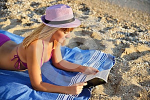 Young woman reading a book on the beach