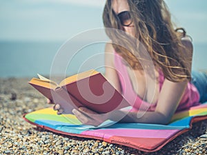 Woman reading book on beach in the summer
