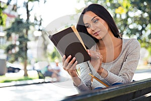 Woman reading book on the bench outdoors