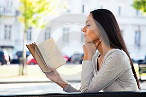 Woman reading book on the bench outdoors