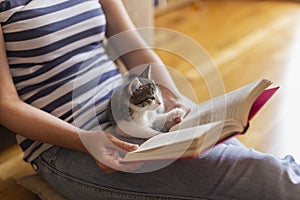 Woman reading book and cuddling kitten