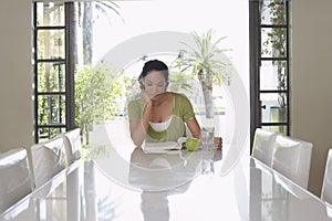 Woman Reading Book At Dining Table