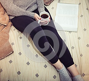 Woman reading a book and drinking coffee in bed