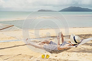 Woman reading a book on hammock beach in free time summer holiday