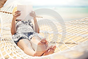 Woman reading a book on hammock beach in free time summer holiday