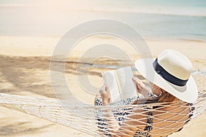 Woman reading a book on hammock beach in free time summer holiday