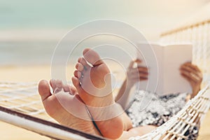 Woman reading a book on hammock beach in free time summer holiday