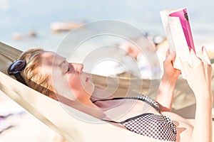 Woman reading book in hammock on the beach