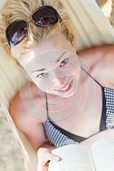 Woman reading book in hammock on the beach
