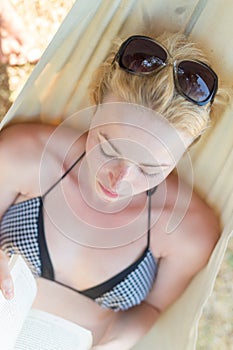 Woman reading book in hammock on the beach