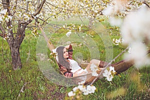 Woman is reading book in hammock in garden