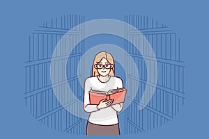 Woman is reading book in library, among shelves with textbooks and looking for right encyclopedia