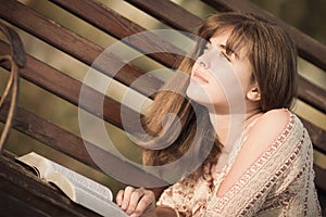 Woman reading a book lying on the bench