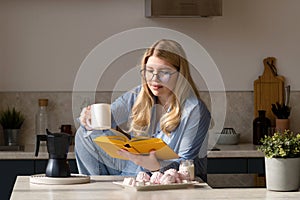 Woman reading book in morning kitchen scene