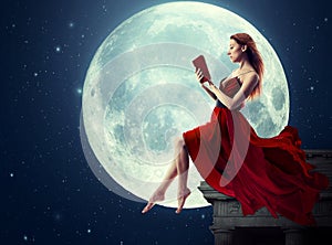 Woman reading book over full moon