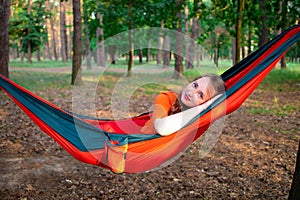 Woman reading a book, relaxing on the hammock in forest, leisure time and summer holiday concept