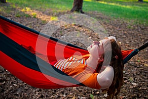 Woman reading a book, relaxing on the hammock in forest, leisure time and summer holiday concept