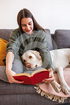 Woman reading a book to a dog