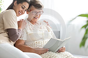 Woman reading book to granddaughter