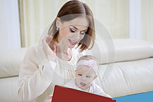 Woman reading a book to her cute baby on couch