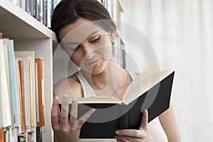 Woman Reading By Bookshelves At Home photo