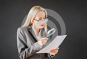 Woman reading business contract with magnifying glass