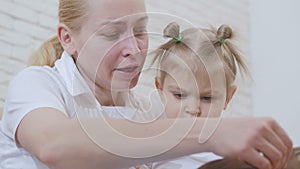 Woman reading a children`s book for a little girl sitting with a child on the couch