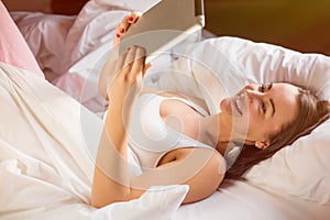 Woman reading ebook on digital tablet in bed