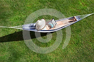 Woman reading ebook lying in hammock