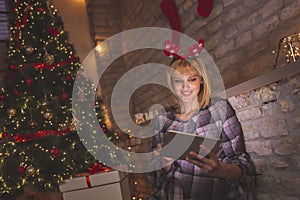 Woman reading an ebook next to a Christmas tree