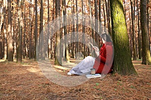 Woman reading an ebook or tablet in an urban park, sit under tree