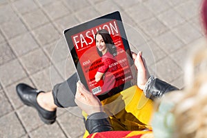 Woman reading fashion magazine on tablet photo