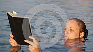Woman reading while floating in the sea