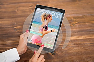 Woman reading healthy lifestyle magazine on tablet photo